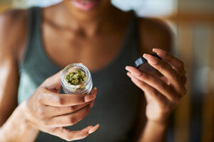 woman opens container of marijuana and debates needing marijuana addiction treatment